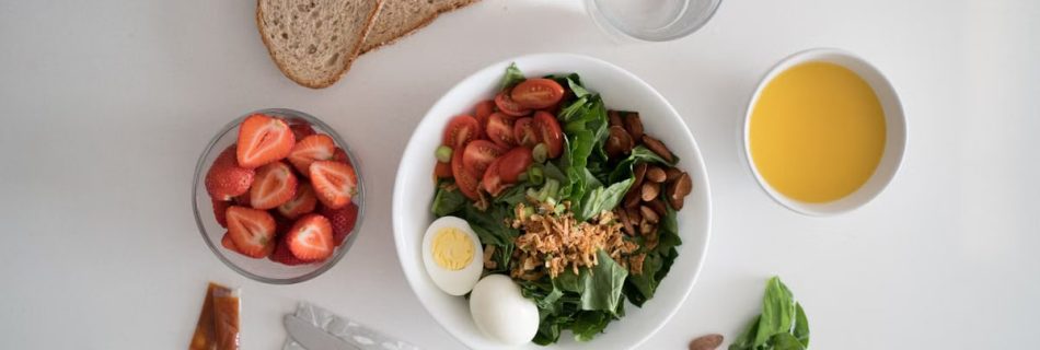 Top view of a nutritious breakfast with salad, eggs, bread, and juice, perfect for a healthy start.
